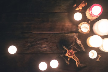 Witch doctor accessories in the light of burning candles on the wooden table background. The...