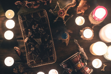 Witch doctor accessories in the light of burning candles on the wooden table background. The witchcraft concept.
