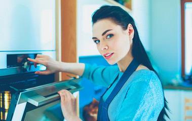 Fototapeta premium Beautiful young woman checking how her cake is doing in the oven