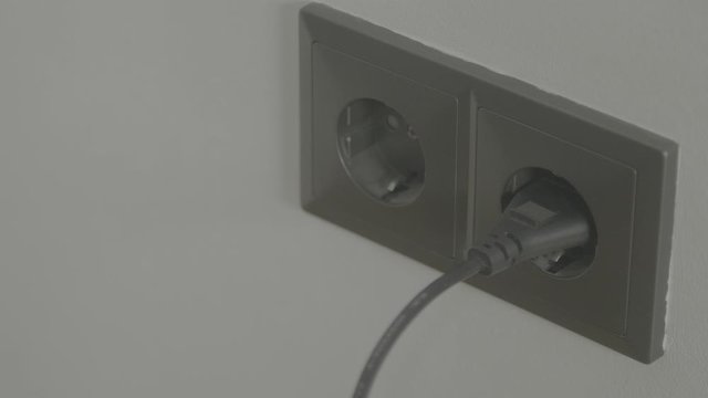 Caucasian man plugs in powerplug in wall 4k