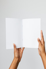 Studio shot of an ethnic or black model holding an A5 or folded letter size blank mockup