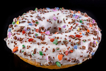 Donut on a dark kitchen table. A delicious sweet dessert decorated with sprinkles.