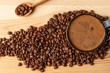 Handmade cup with coffee on the table. Countertop made of wood. Coffee beans. Freshly fried arabica.