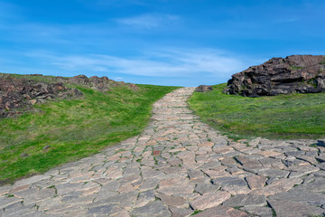 A road made of natural stone leading to the top of the mountain. Summer landscape.