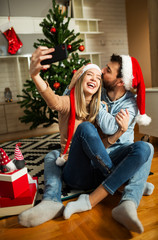 Obraz na płótnie Canvas Happy couple using phone to make selfie in home 
