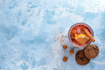 Glass of tasty mulled wine with cookies on color background