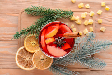 Glass of tasty mulled wine on wooden background