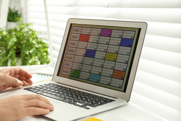 Man using calendar app on laptop in office, closeup