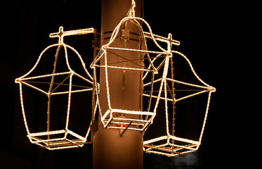 light lanterns hanging on a metal column in front of a black background