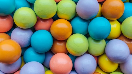 Bright multi-colored background from small wooden colored balls. Application in the design of catalogs of stores for children, packaging of goods, printing. Top view.  Long banner format.