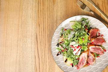 Delicious salad with roasted duck breast served on wooden table, flat lay. Space for text