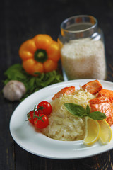 Rice porridge with vegetables and rabbit in sauce on a black wooden table.