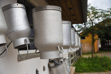 milk churns hanging outside farm for cows