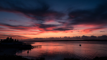 Obraz premium Colourful clouds at dawn over a bay