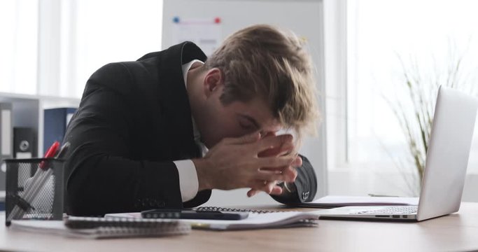 Frustrated overworked businessman sleeps on office desk