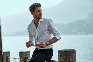 Stylish man in white classic shirt, looking at the mountains view - obrazy, fototapety, plakaty