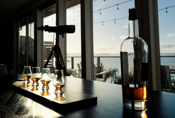 Old fashioned whiskey tasting with bottle on table sea view.