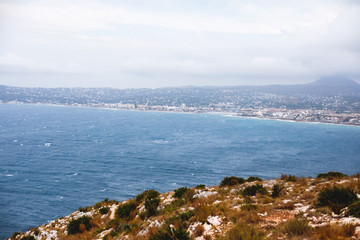 Beautiful super wide-angle aerial view of Xabia, Javea, Marina Alta with harbor and skyline, mountains, beach and city, seen from Cabo de San Antonio viewpoint, province of Alicante, Valencia, Spain