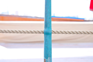 A detail view of a bronze stanchion and a hempen lifeline, details of deck equipment on a classic sailing yacht.