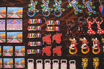 View of traditional tourist souvenirs and gifts from Spain, Alicante, Valencia with toys, bull figures, flamenco dancer dolls, fridge magnets with and key ring keychain, in local vendor souvenir shop