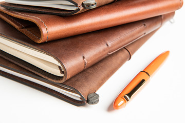 Leather-Bound Journals And An Orange Fountain Pen