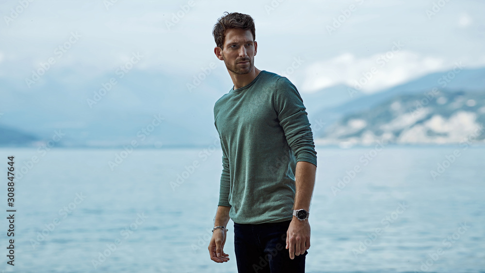 Wall mural handsome man in casual style clothes over lake and alps view