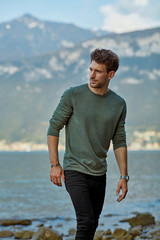 Handsome man walking on the beach over mountains background 