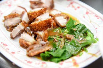 Crispy Pork Belly Stir Fry With Chinese Kale in white plate at restaurant