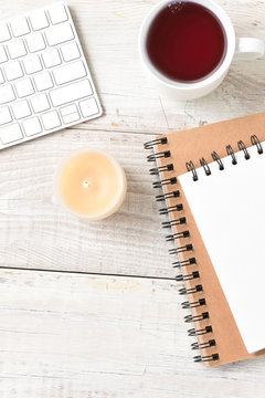 White flat lay still life home office desk, with coffee, keyboard pads and candle, verticle format with copy space.