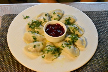 Traditional Polish dumplings with goose meat served with cranberry sauce and chopped parsley. Portion consists of ten boiled semicircular pieces made from a chewy wheat based dough. Gdansk, Poland