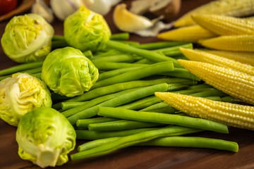 Brussels sprouts, baby corn and green beans on a wooden board
