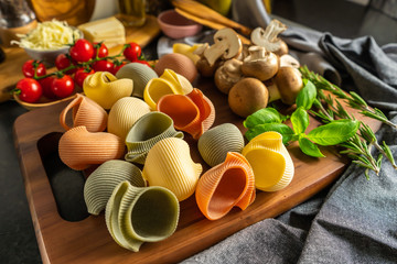 Italian pasta, colored shells, Italian colored lumaconi on a wooden board