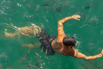 People swimming with fish near boat in Blue Lagoon in Ilha Grande, Angra dos Reis Bay of the state...