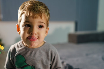 Portrait of one small caucasian cute boy three years old at home showing his tongue loll out