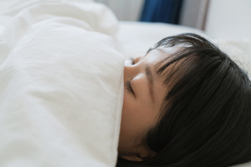 young asian woman use quilt cover her mouth on bed, sleeping