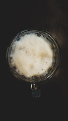 Light, fresh and tasty beer with a white fluffy foam on a dark background. Beer Day Celebration. Alcoholism concept. Portrait capture