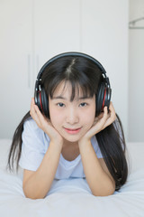 asian young woman listen to music headphone on bed