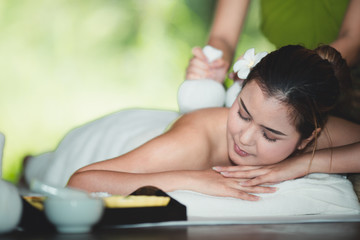 Obraz na płótnie Canvas Beautiful young asian woman lying relaxing and smile on the bed having a massage with herbal compresses in a spa. Thai massage for health.