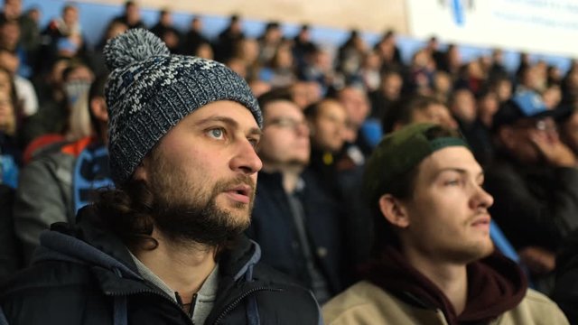 Person spectator fan watch game hockey closeup view excitedly looking match in crowd 4K. Hockey fan with serious face enter score game at stadium. Man nervously watch game close up attention spectator
