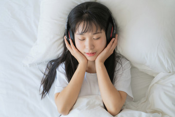 asian young woman listen to music on bed