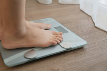 Fototapeta premium feet on digital weighing scale on wooden floor