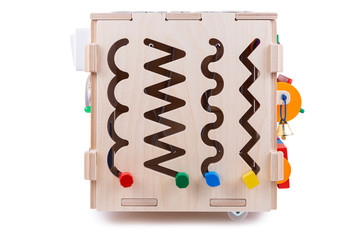 Сlose-up of a labyrinth with multi-colored puzzles on a wooden busy board- educational toy for children, babies on a white isolated background. A toy for entertaining children and resting parents