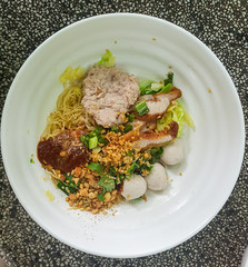 Thai noodles style with pork and meat ball in white bowl.Dry noodle spicy call 