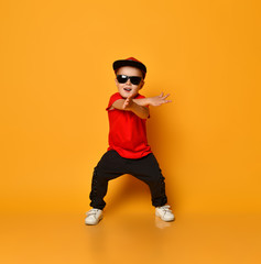 Happy little boy dancing on a yellow background