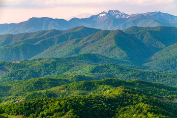 Layers of mountains in the haze during sunset. Beautiful sunset in the mountains. Beautiful sunset in a hilly valley with villages and fog in the lowlands.