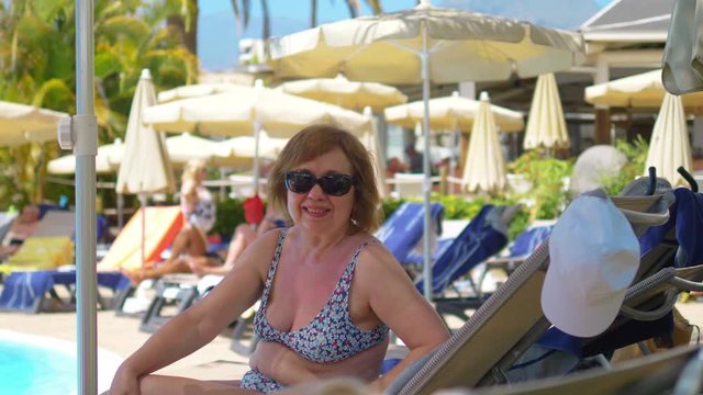 Senior woman relaxing on the sunbed in 4K slow motion 60fps