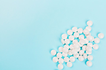 White pills on a pastel blue background. Flat lay, top view, overhead, mockup, template, copy space. Pharmacy and medical concept