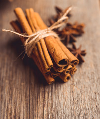 Bundle of cinnamon and anise stars on the rustic wooden background. Selective focus. Shallow depth of field.