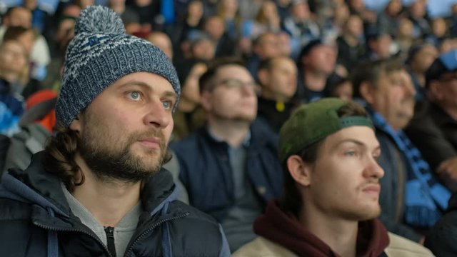 Hockey fan with serious face enter score game at stadium. Man spectator fan watch game hockey closeup view excitedly looking match in crowd 4K. Guy nervously watch game close up attention spectator.