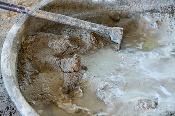 Bucket cement mix with on construction site the ingredients. Brick, Stone, Mortar, Sand.
